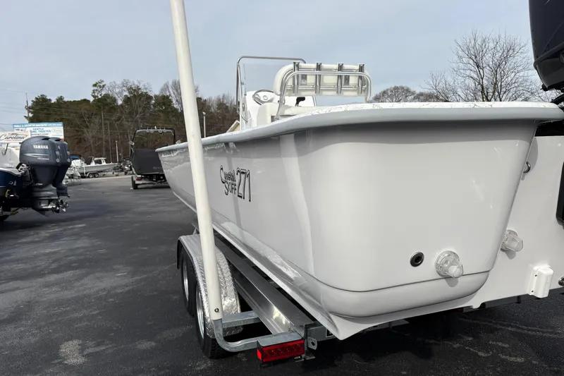 Slide: The Image of 2026 Coastal Skiff 271 boat on trailer, parked outdoors, featuring sleek white design. - 2