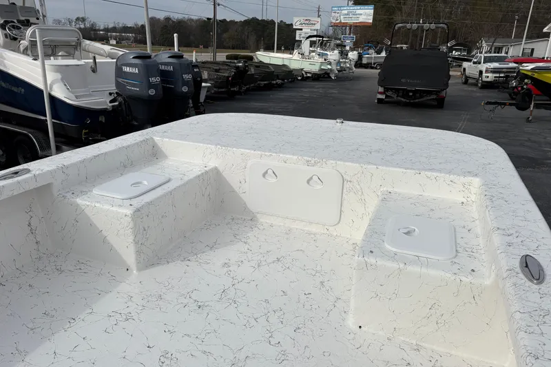 Slide: The Image of 2026 Coastal Skiff 271 boat deck with storage compartments, displayed at a dealership. - 6