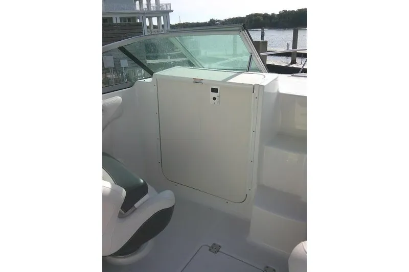 Slide: The Image of 2016 Chaparral 225 SSi boat interior with seating and windshield, docked by the water. - 16