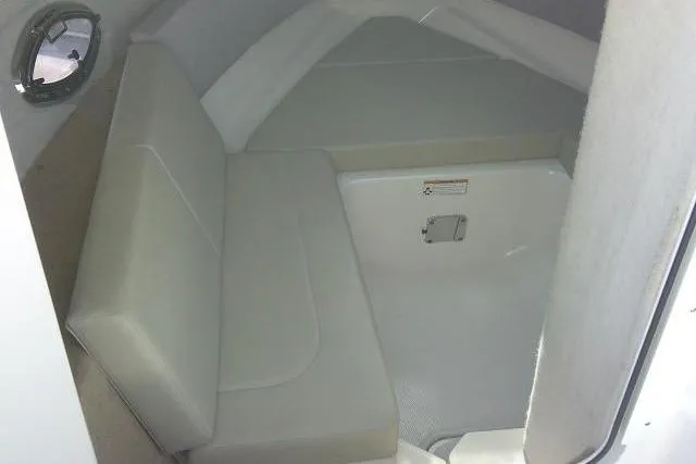 Slide: The Image of 2016 Chaparral 225 SSi boat interior cabin with cushioned seating and porthole. - 35