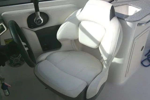 Slide: The Image of Captain's seat in 2016 Chaparral 225 SSi boat, featuring white upholstery and steering wheel. - 47