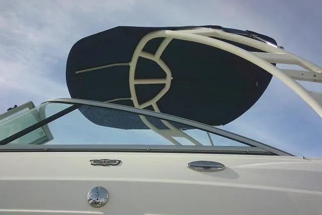 Slide: The Image of 2016 Chaparral 225 SSi boat with sleek design and canopy against blue sky. - 7