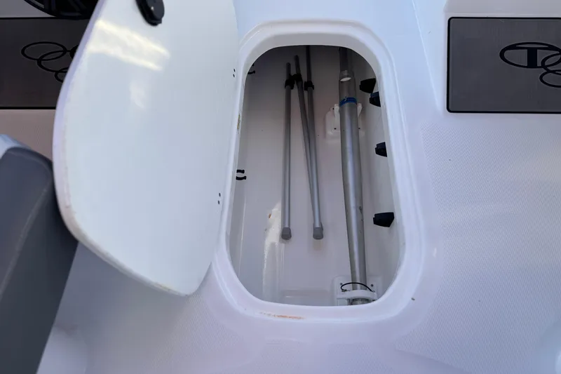 Slide: The Image of Open storage compartment in 2024 Tahoe T21 boat, showing poles and equipment. - 16