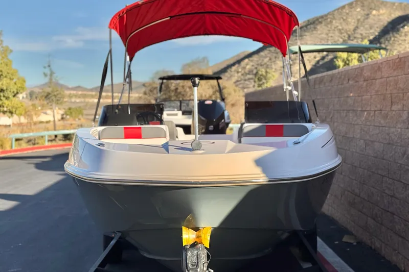 Slide: The Image of 2024 Tahoe T21 boat with red canopy, parked outdoors on a sunny day. - 2