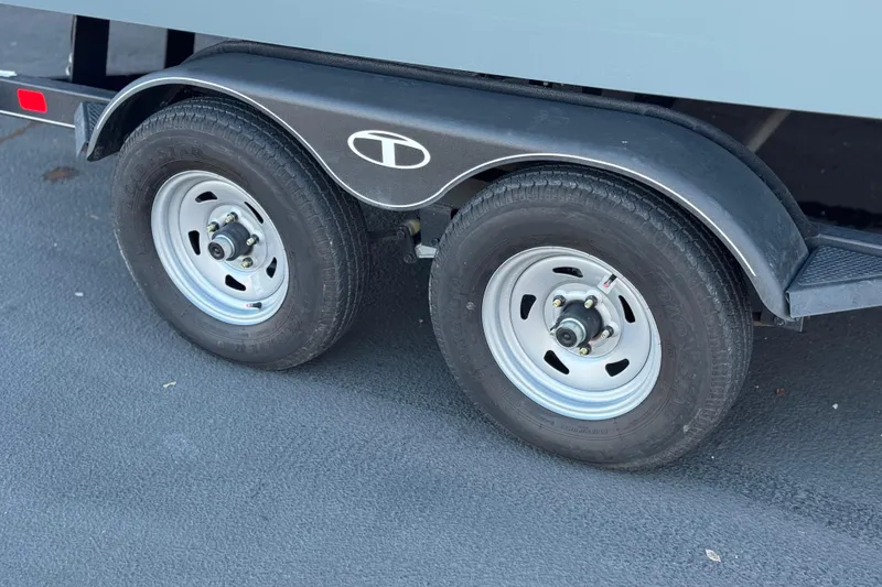 Slide: The Image of 2024 Tahoe T21 trailer wheels on asphalt, featuring dual tires and fender. - 23