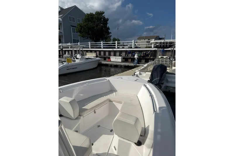 Slide: The Image of 2024 Aquasport 2200 Center Console boat docked at marina under cloudy sky. - 2