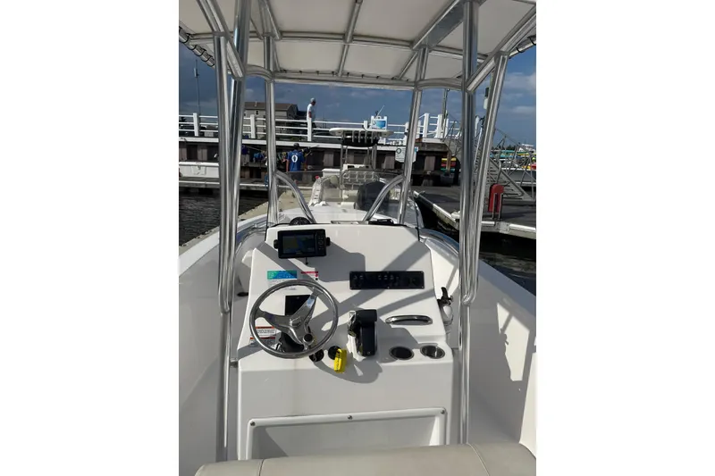 Slide: The Image of 2024 Aquasport 2200 Center Console boat interior at dock, featuring steering and navigation equipment. - 6