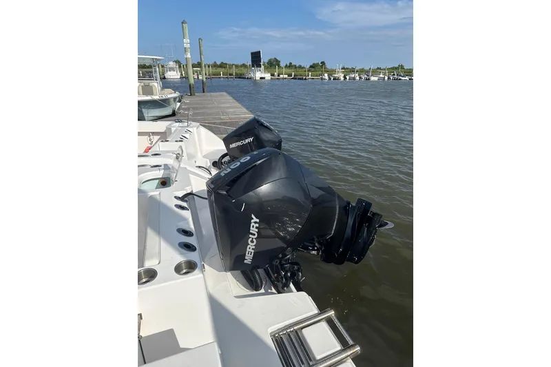 Slide: The Image of 2024 Aquasport 2200 Center Console with dual Mercury outboard engines docked by the water. - 7
