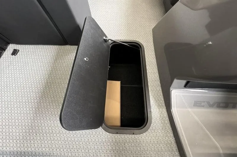 Slide: The Image of Open storage compartment in 2026 Evotti 523CS vehicle interior, featuring carpeted flooring. - 16