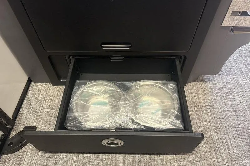 Slide: The Image of 2026 Bennington 24 MSL boat storage drawer with wrapped items on carpeted floor. - 17