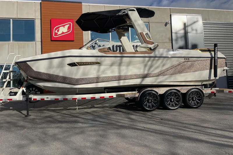 The Image of 2026 Nautique Super Air Nautique G25 Paragon boat on trailer outside dealership. - 1