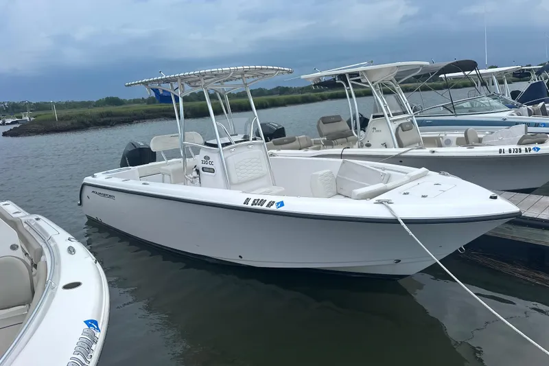 The Image of 2024 Aquasport 2200 Center Console boat docked on a calm waterway. - 1
