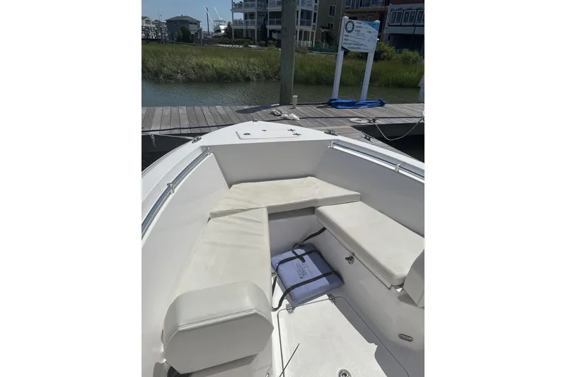 Slide: The Image of 2024 Aquasport 2200 Center Console boat interior with cushioned seating at dock. - 6