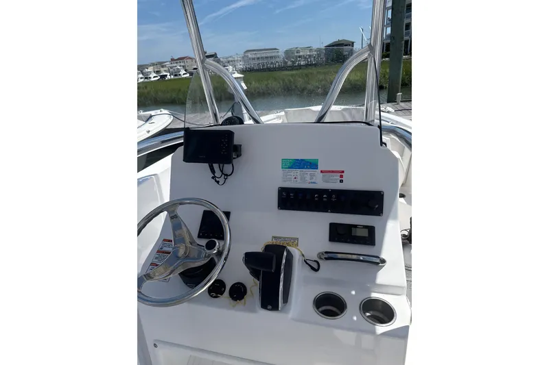 Slide: The Image of 2024 Aquasport 2200 Center Console boat dashboard with steering wheel and controls. - 7