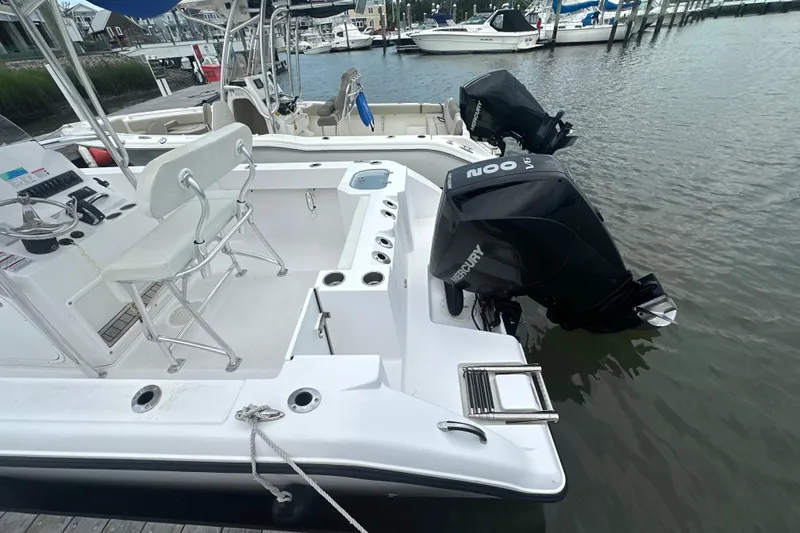 Slide: The Image of 2024 Aquasport 2200 Center Console boat with dual Mercury outboard engines docked at marina. - 9