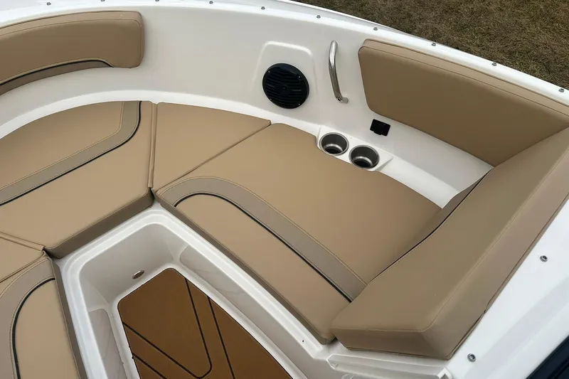 Slide: The Image of 2026 Bayliner V20 boat interior with tan seating, cup holders, and speaker. - 15