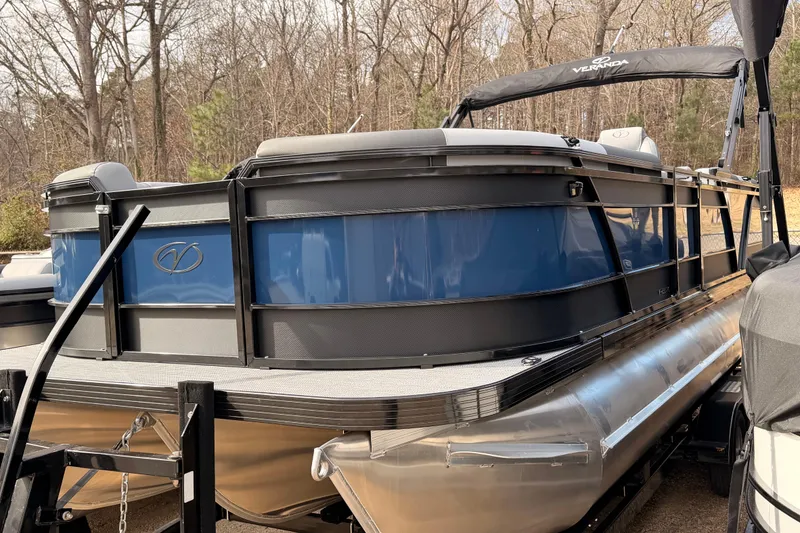 Slide: The Image of 2026 Veranda VR 235 RC pontoon boat with blue and black design, parked outdoors. - 3