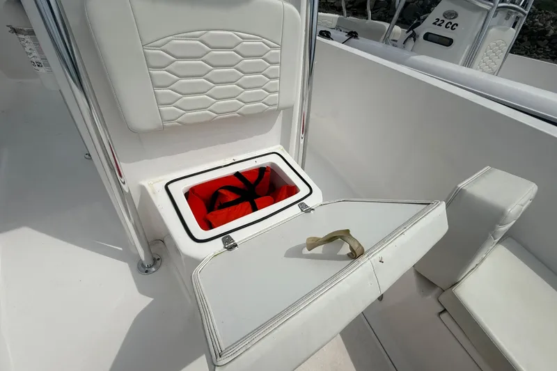 Slide: The Image of 2024 Aquasport 2200 Center Console boat with open storage compartment and life jacket. - 10