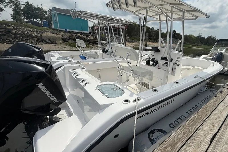 Slide: The Image of 2024 Aquasport 2200 Center Console boat docked, featuring Mercury engines and spacious seating. - 2