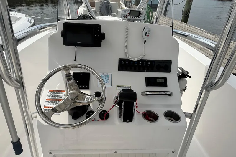 Slide: The Image of 2024 Aquasport 2200 Center Console boat dashboard with steering wheel and navigation equipment. - 6