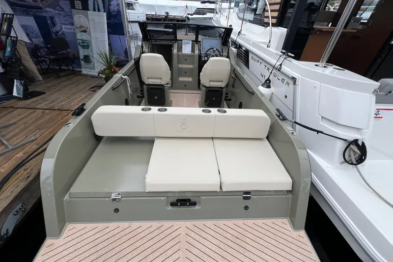 Slide: The Image of 2024 X Shore 1 electric boat interior with seating and helm, docked beside another vessel. - 3