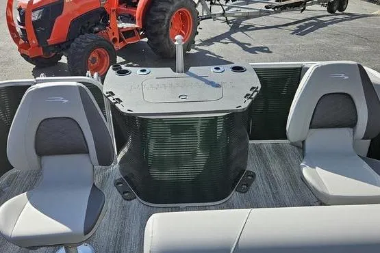 Slide: The Image of 2026 Bennington 22 S Fish boat interior with seating and console, parked near an orange tractor. - 17