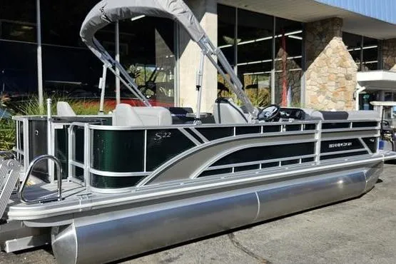 Slide: The Image of 2026 Bennington 22 S Fish pontoon boat with canopy, parked outside a building. - 3
