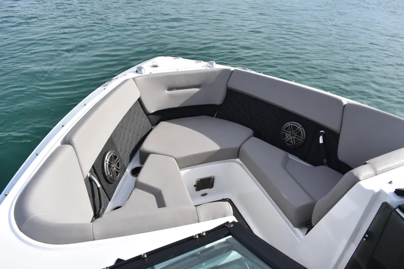 Slide: The Image of 2022 Four Winns H2 OB boat interior with cushioned seating and speakers on calm water. - 11