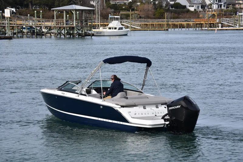 Slide: The Image of 2022 Four Winns H2 OB boat cruising on a calm waterfront with dock in background. - 5