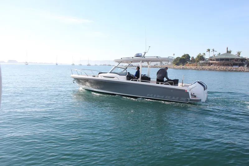 Slide: The Image of 2024 Nimbus T9 boat cruising on a sunny, calm sea near a coastal area. - 2