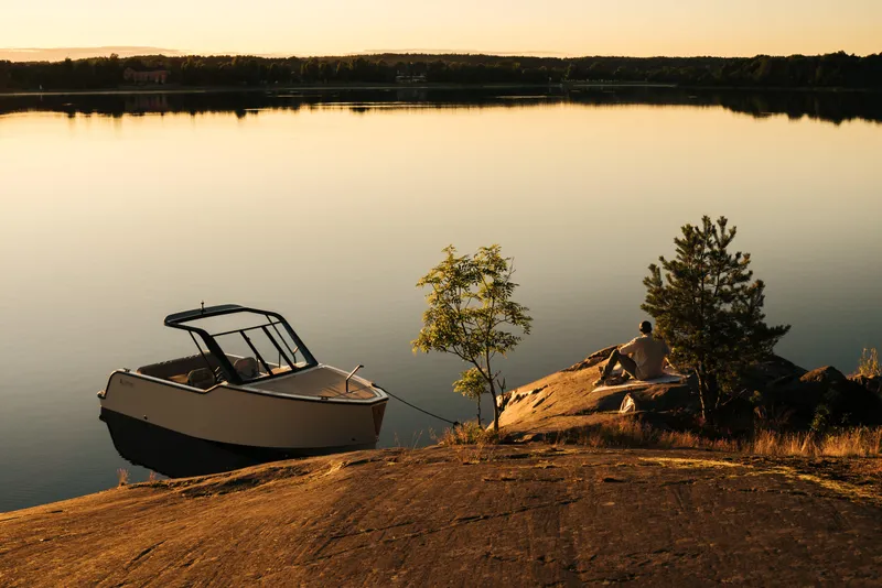 Slide: The Image of 2024 X Shore 1 boat moored by a tranquil lakeside at sunset. - 12