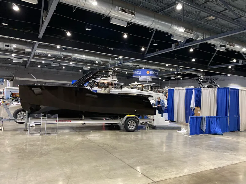 Slide: The Image of 2024 X Shore 1 electric boat displayed indoors on a trailer at a boat show. - 2