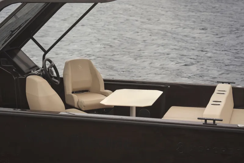 Slide: The Image of 2024 X Shore 1 electric boat interior with beige seating and table on water. - 8