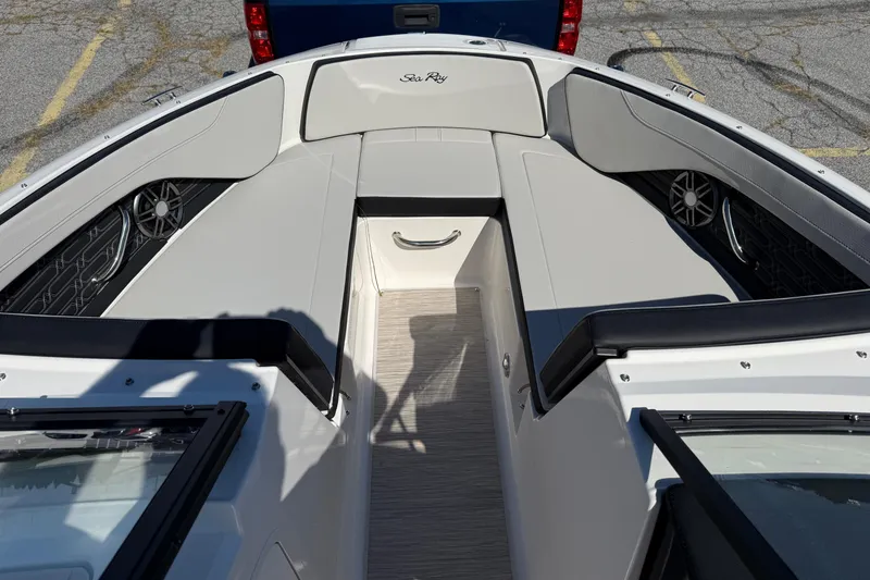 Slide: The Image of 2026 Sea Ray SPX 210 boat interior with seating and speakers, parked on pavement. - 11