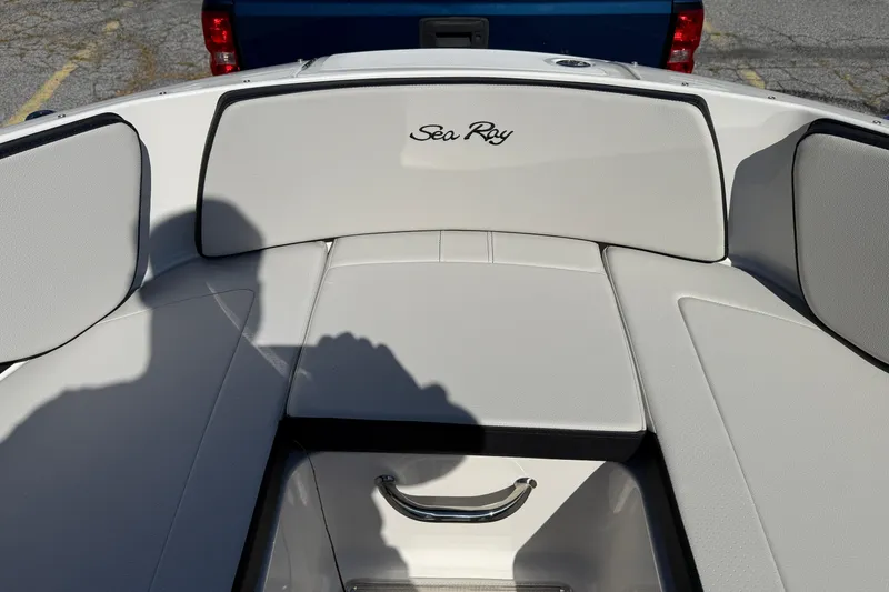 Slide: The Image of 2026 Sea Ray SPX 210 boat interior with white cushioned seating and storage compartment. - 12