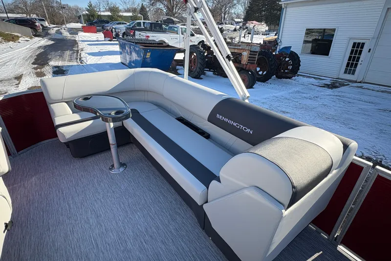 Slide: The Image of 2026 Bennington 20 SL pontoon boat interior with plush seating and table, snowy background. - 14