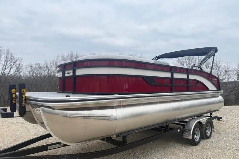Slide: The Image of 2026 Lowe SS 230 WV pontoon boat on trailer, red and silver design, parked outdoors. - 1