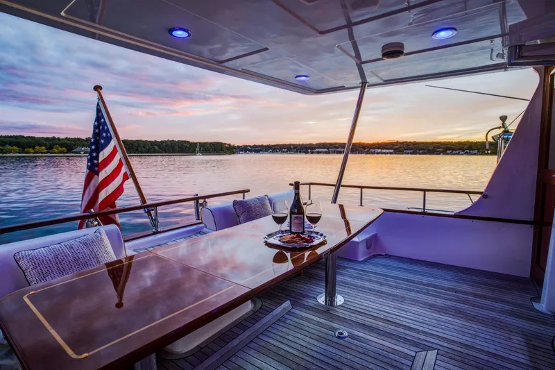 Slide: The Image of Luxurious 2006 Grand Banks 59 Aleutian RP yacht deck at sunset with wine and American flag. - 57