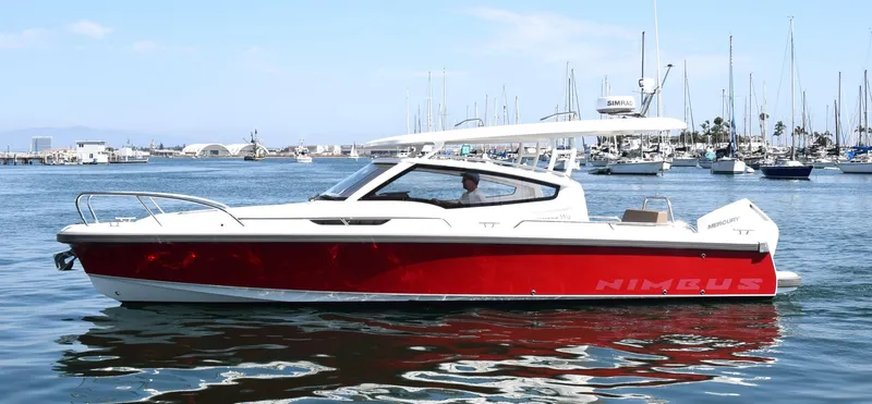 Slide: The Image of Red 2024 Nimbus W9 boat cruising in a marina with sailboats in the background. - 17