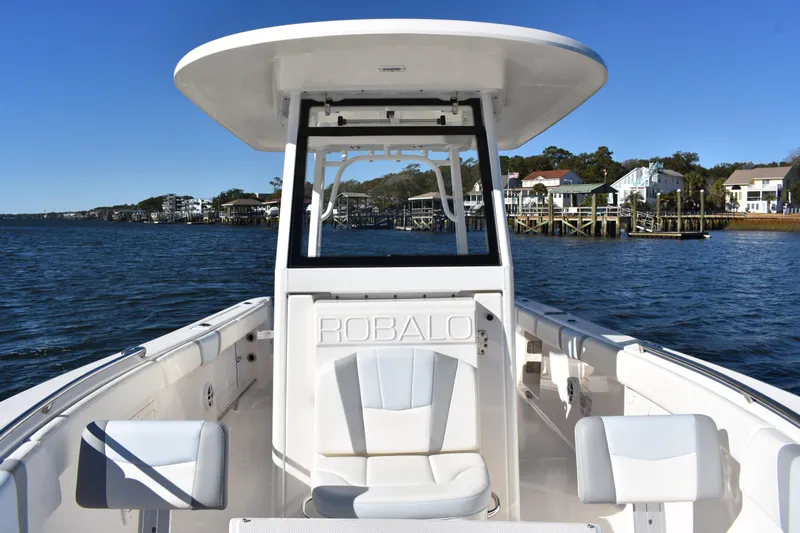 Slide: The Image of 2022 Robalo R272 Center Console boat on water, with coastal homes in the background. - 12