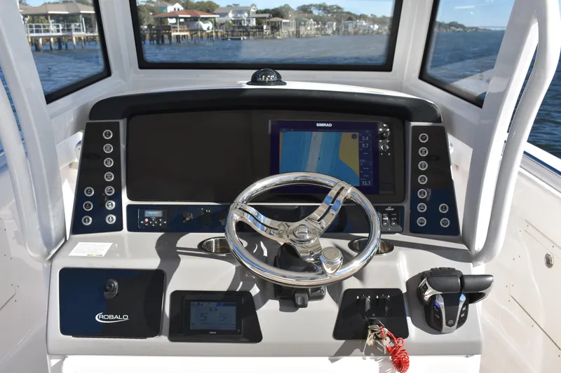 Slide: The Image of 2022 Robalo R272 Center Console boat dashboard with steering wheel and navigation display. - 17