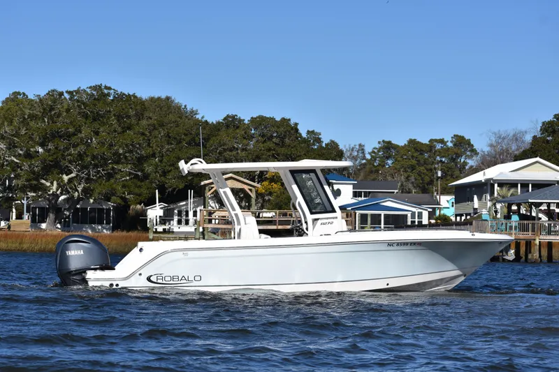 Slide: The Image of 2022 Robalo R272 Center Console boat on water near shoreline homes. - 5