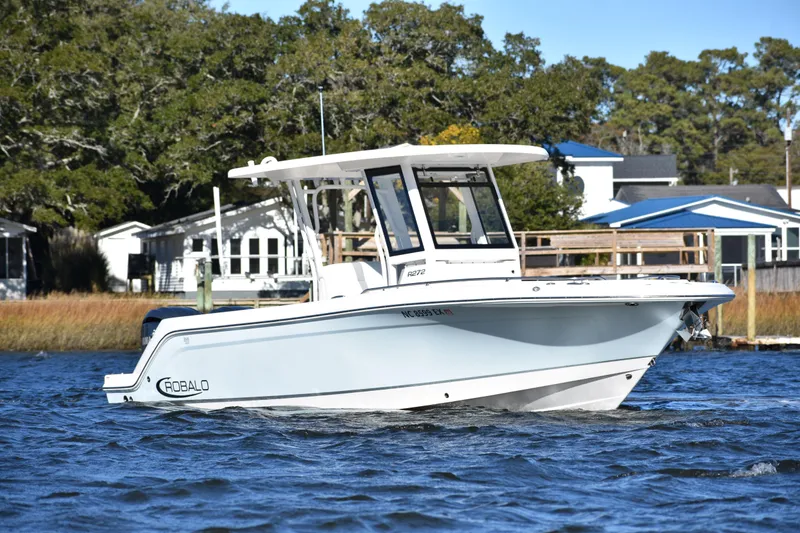 Slide: The Image of 2022 Robalo R272 Center Console boat on water, surrounded by trees and houses. - 6