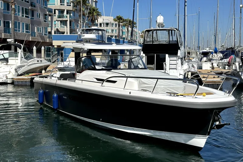 Slide: The Image of 2023 Nimbus T11 boat docked in a marina with modern buildings in the background. - 13