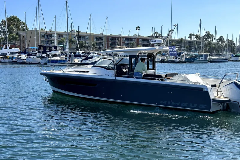 Slide: The Image of 2023 Nimbus T11 boat cruising in a marina with sailboats and buildings in the background. - 15