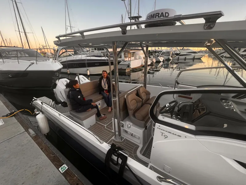 Slide: The Image of Two people sitting on a Nimbus T9 #103 Twin Engine boat docked at a marina. - 14
