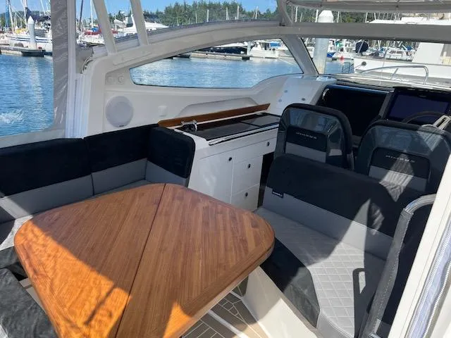Slide: The Image of 2023 Nimbus W9 boat interior with seating and wooden table, docked at marina. - 25