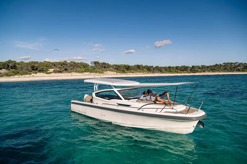 Slide: The Image of 2023 Nimbus Weekender 9 boat cruising near a scenic coastline under a clear blue sky. - 36
