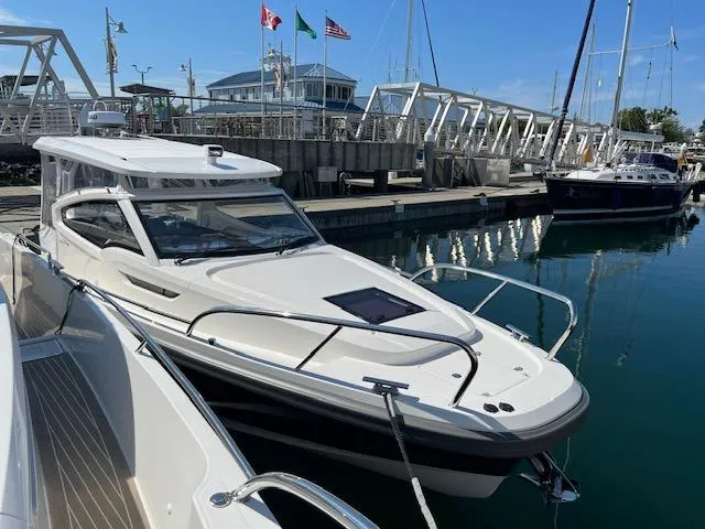 Slide: The Image of 2023 Nimbus W9 boat docked at marina with flags and sailboats in background. - 4