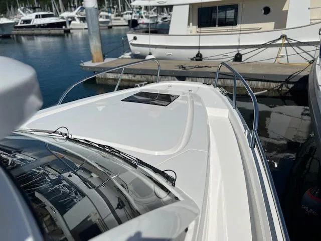 Slide: The Image of 2023 Nimbus W9 boat docked at marina, sleek white design, stainless steel railings. - 8